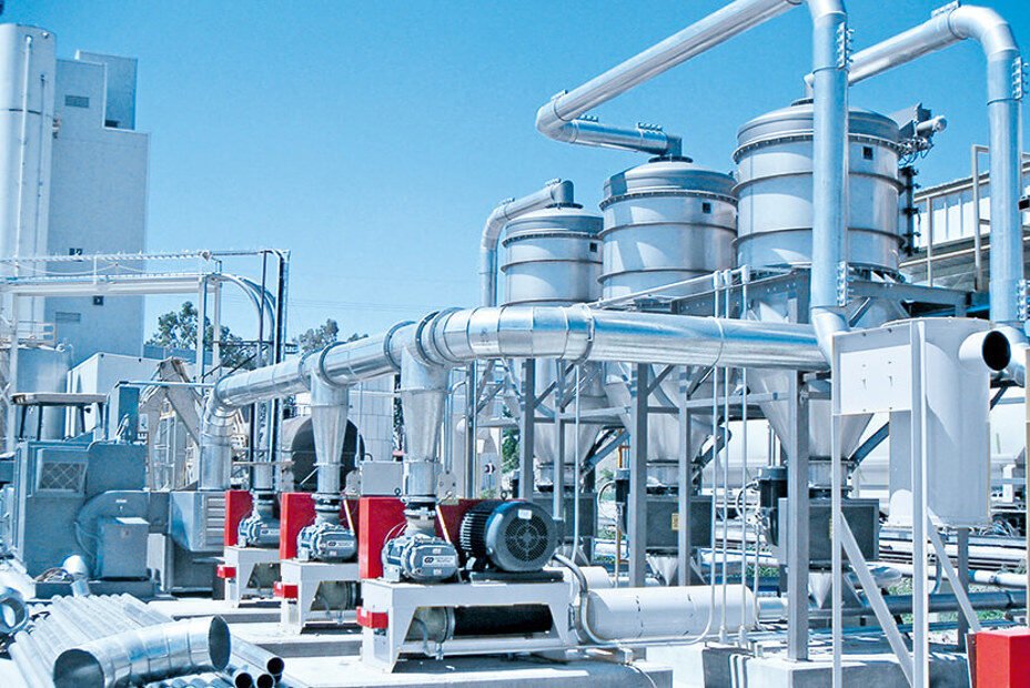 A modern industrial facility featuring pneumatic conveying systems with multiple interconnected pipes and storage units, ideal for efficient powder handling processes.